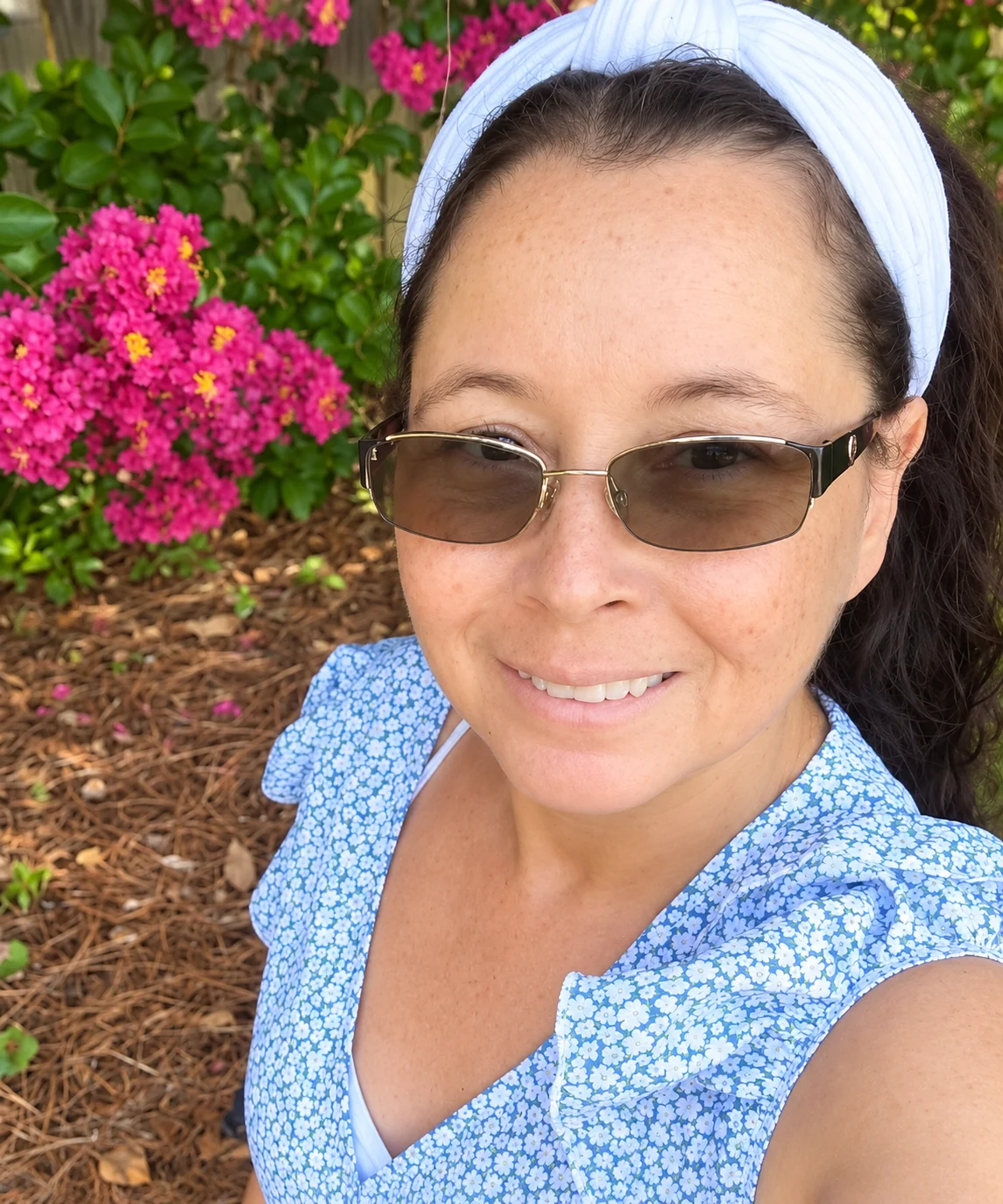 Johanna smiling outdoors surrounded by pink flowers